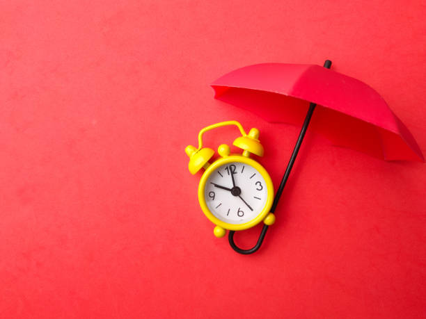 istock A yellow alarm clock with red umbrella on a red background with copy space. 1439105461