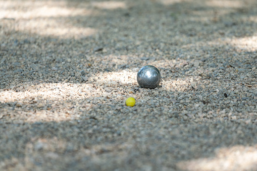A steel ball of Petanque sport which is placed on gravel rock field. Sport equipment object photo, close-up.