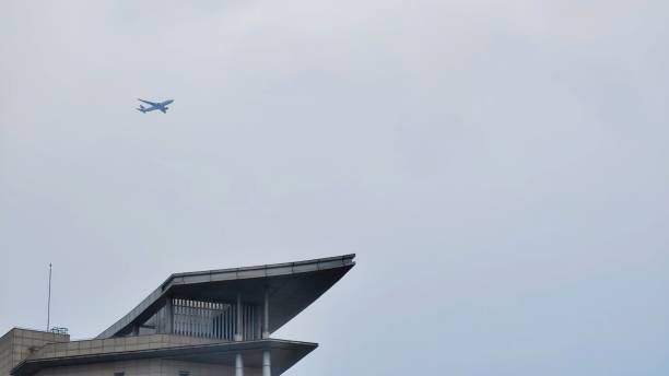 istock Plane flying over a building against gloomy sky 1439119044