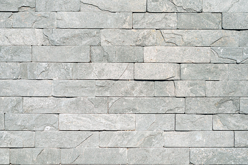 background, texture of a wall made of facing bricks of gray non-uniform color.