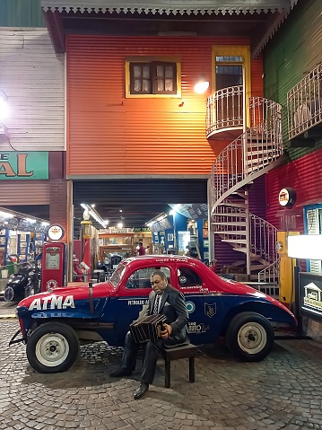 Buenos Aires, Argentina – October 03, 2022: Tribute to tango bandoneon player Anibal Troilo Pichuco. La Boca quarter typical colorful sheet metal houses, spiral staircase and cobblestone street