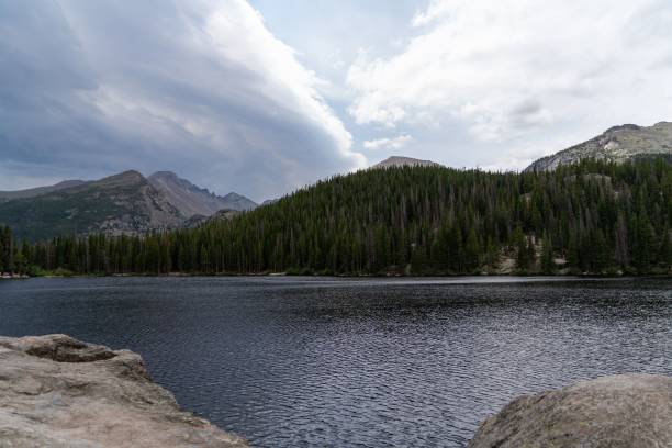 istock Lake surrounded by lush green dense forests under blue cloudy sky 1439133941