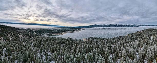 istock Panoramic view a fir tree forest covered in snow and surrounded by lake on a cloudy day 1439134952