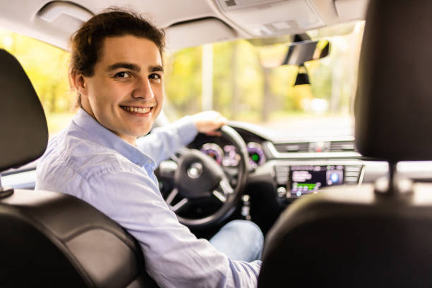 istock transport, vehicle and driving concept. Young man or car driver looking back 1439134977