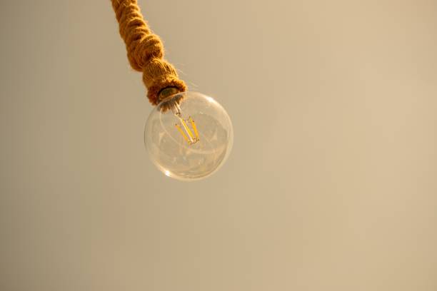 Bulb is hanging from a rope on a pale brown background