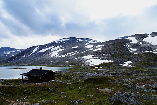 A rural Norwegian cottage near the lake surrounded by high rocky mountains at Atlantic Ocean Road, Norway