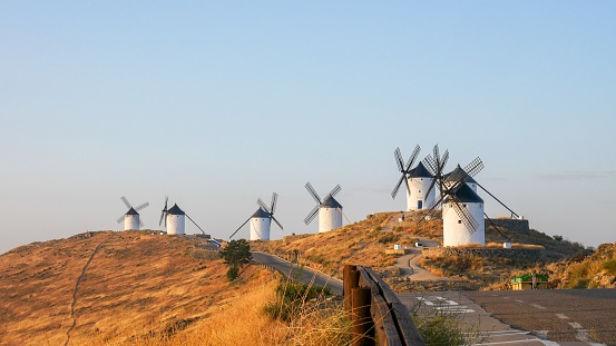 A panoramic shot of beautiful Windmills on a grassy hill in  Consuegra, Spain