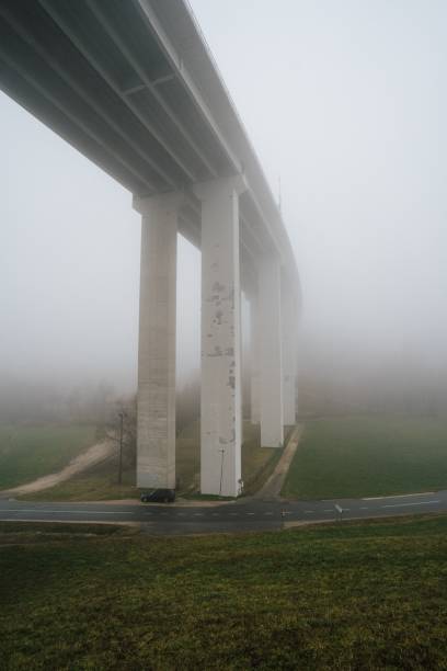 бетонный мост на холме, окруженный зеленью, покрытой туманом под облачным небом - pacific ocean coastline rain california стоковые фото и изображения