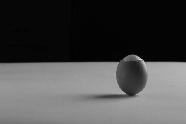 istock Black and white of a half-peeled egg on a table. 1439140556