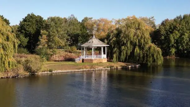 an aerial shot over a small bandstand near a lake in watermead park