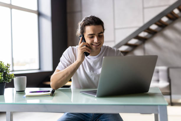 istock Casual businessman working at office desk, using mobile phone and laptop computer, typing, making phone call 1439141362