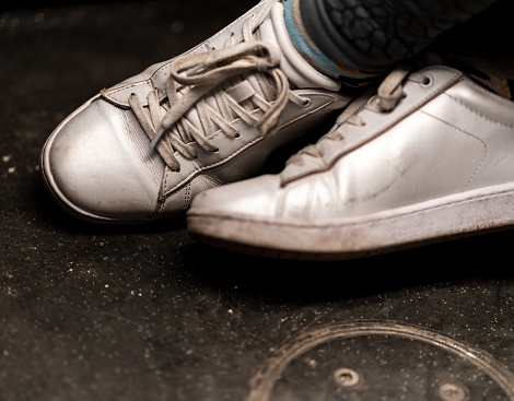 A high angle closeup shot of worn-out white sneakers