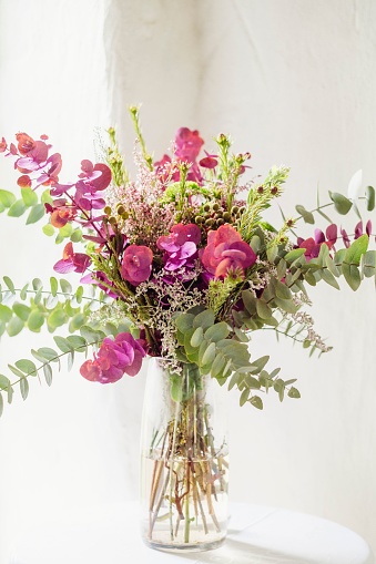 A vertical shot of a beautiful bouquet of mild flowers in a glass vase