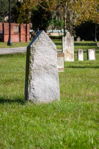 istock Unmarked Gravestone on grass field on a sunny day, vertical shot 1439141866