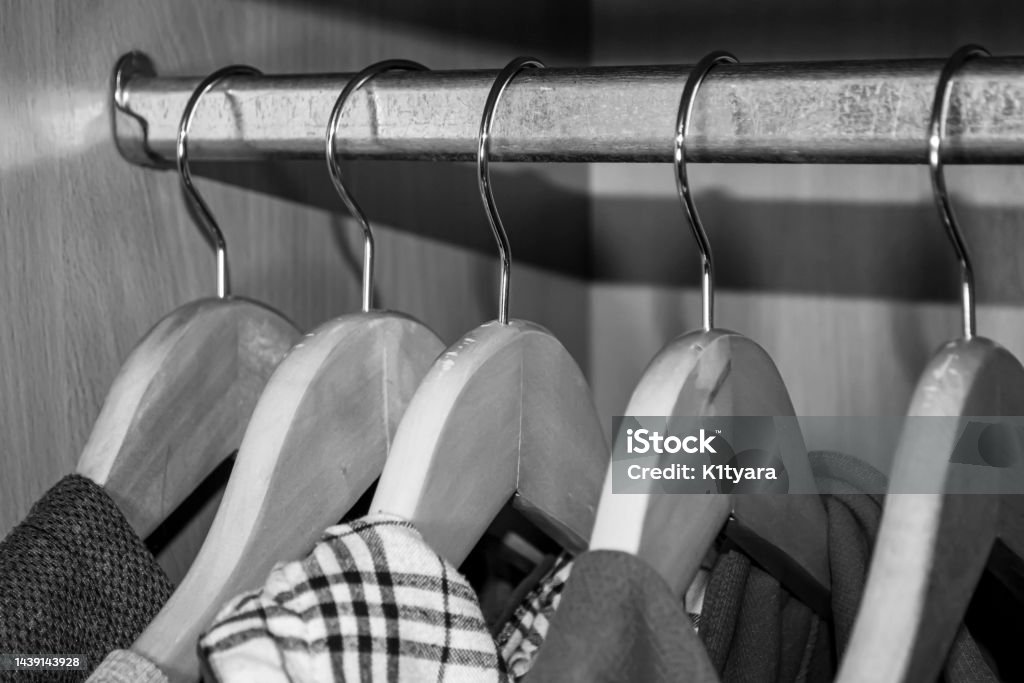 Kleiderbügel mit Kleidung hängen im Schrank. Die Dinge hängen an hölzernen Kleiderbügeln. Schwarz-Weiß-Foto eines Kleiderbügels in einem Schrank mit Kleidung. - Lizenzfrei Kleiderstange Stock-Foto