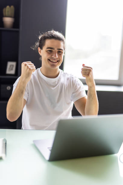 istock Excited young man winner sit at home table looking at laptop screen celebrating online success victory euphoric overjoyed by internet sport bet win got new job opportunity or loan approval in email 1439144372