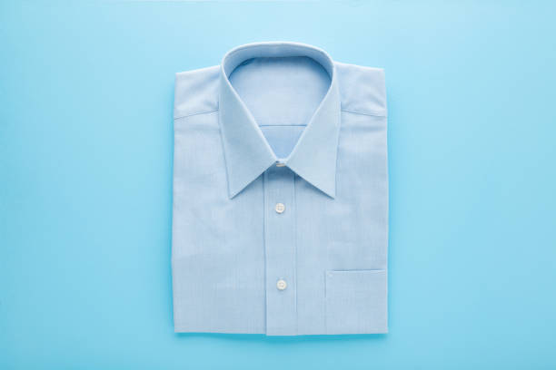 istock Folded classic shirt on light blue table background. Pastel color. Closeup. Top down view. Male clothes. 1439145988