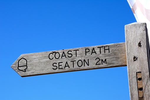 Wooden coastal path sign for Seaton against a blue sky, Beer, Devon, UK, Europe,