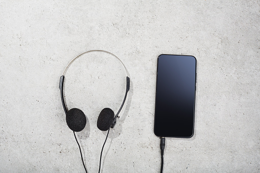 Smart phone and vintage headphones on concrete background. Summer and music