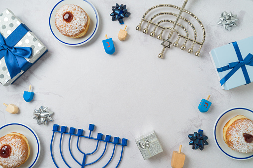 Jewish holiday Hanukkah frame border background with traditional donuts, menorah and gift box. Top view, flat lay