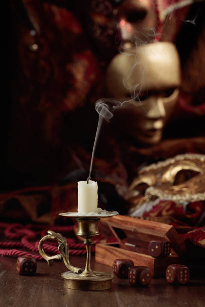 istock Extinguished candle, dice, and carnival masks on an old wooden table. 1439161587