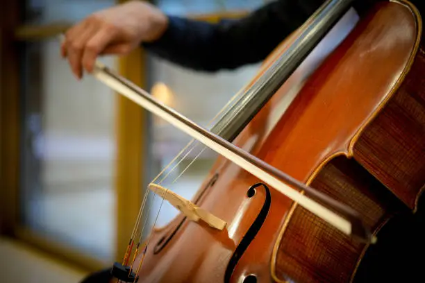 Detail view of an unrecognizable man playing the cello in public.
