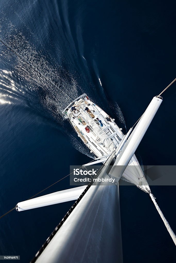 Sailboat from above Sailing crew of three people on sailboat sailing. High angle view from top of mast. All 3 people model released. Canon 5DMkII. Sailboat Stock Photo