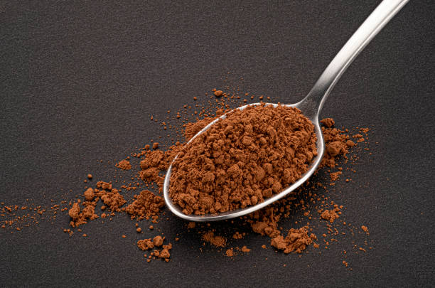 istock Cocoa powder in spoon on black background 1439169886