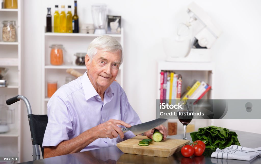 Senior homme assis dans un fauteuil roulant et de préparer des repas - Photo de Adulte libre de droits