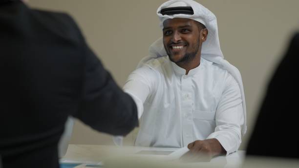 istock Businessmen shacking hands together showing successful contract agreement standing beside secretary business officer clapping hands with gladness in comfortable meeting room 1439171450