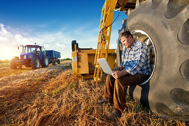 Farmer counts yields on a computer Farmer and laptop agricultural machinery stock pictures, royalty-free photos & images