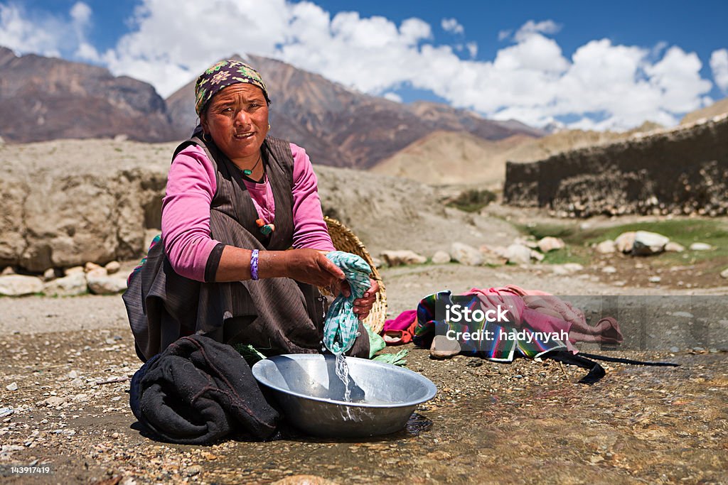 Tibétain femme se laver les vêtements de la rivière.   Mustang. - Photo de Tibétain libre de droits
