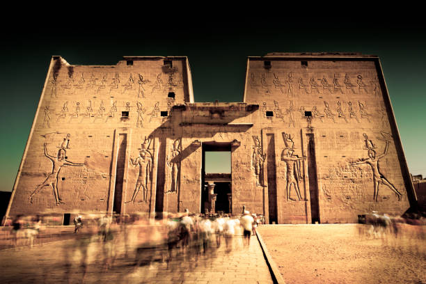 Darkness in Edfu Visitors in the temple of Edfu - Egypt - Long exposure picture and added some grain. hieroglyphics photos stock pictures, royalty-free photos & images