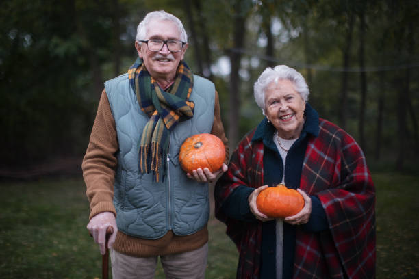 istock Senior couple with pumpkins in autumn forest. 1439175570