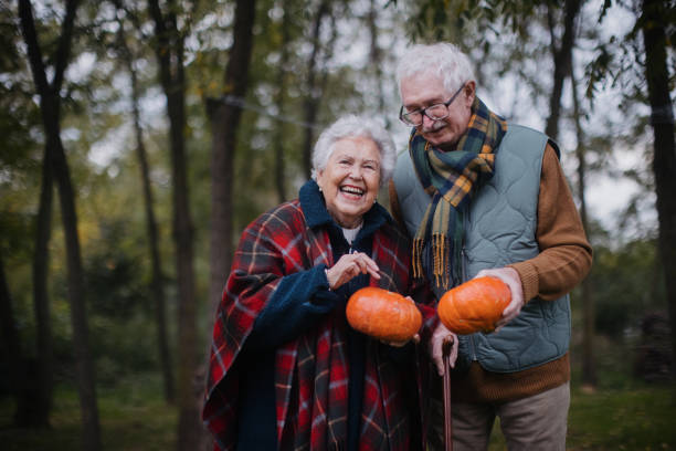 Senior couple with pumpkins in autumn forest.