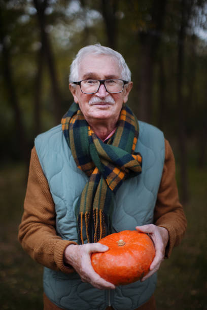 istock Senior man with pumpkins in autumn forest. 1439175673