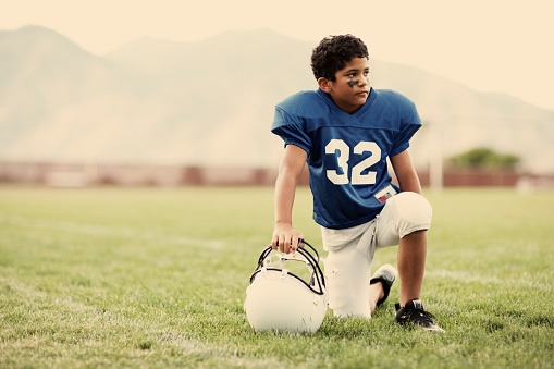 A young American boy dreams of touchdowns on the football field.