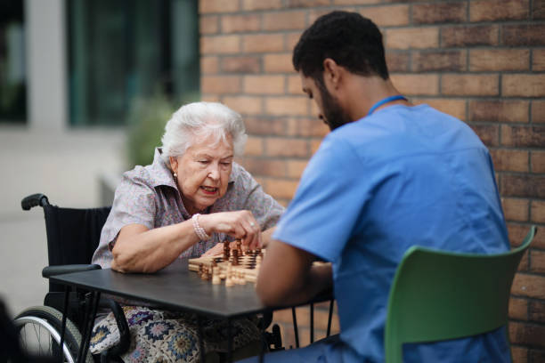 istock Caregiver playing chess with his client outdoor at cafe. 1439176235