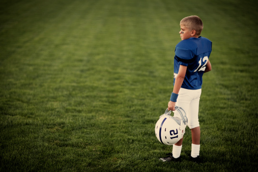 A young American boy dreams of throwing touchdowns on the football field.