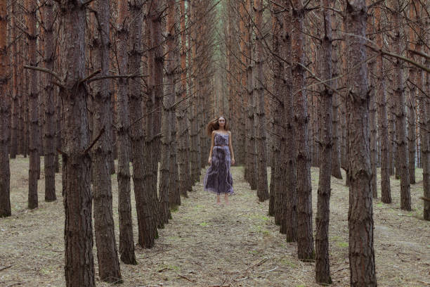 Young woman dressed like an evil queen standing in the forest.