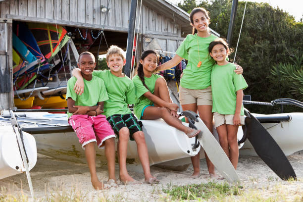 adolescent et les enfants en face des équipements de sports nautiques shack - animateur de colonie de vacances photos et images de collection