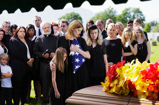 A mother and two children standing graveside at a funeral.