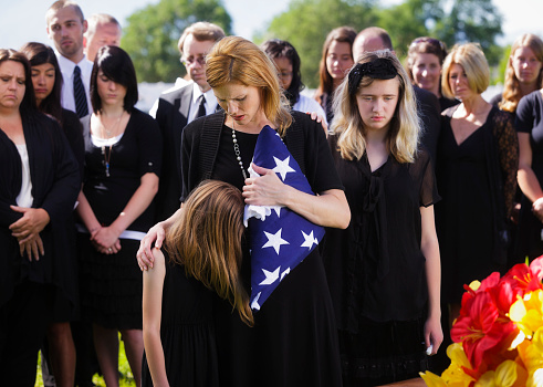 A mother and two children standing graveside at a funeral.