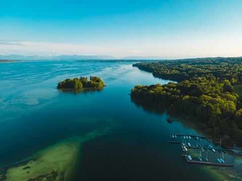 Aerial view of the Rose Island in Lake Starnberg. Deep blue water with beautiful view of a small harbour with sailing boats and the Alps background