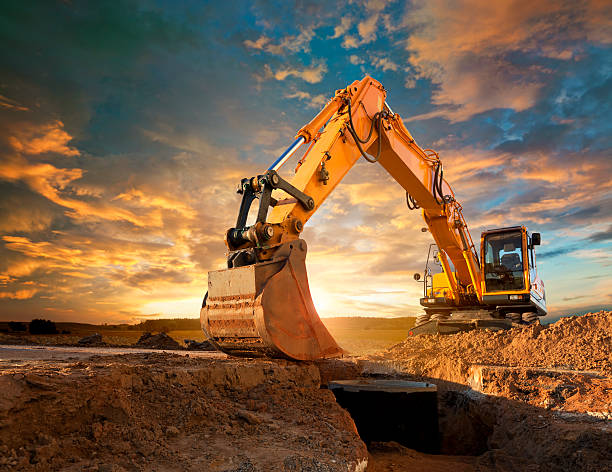 Excavator at a construction site against the setting sun. stock photo