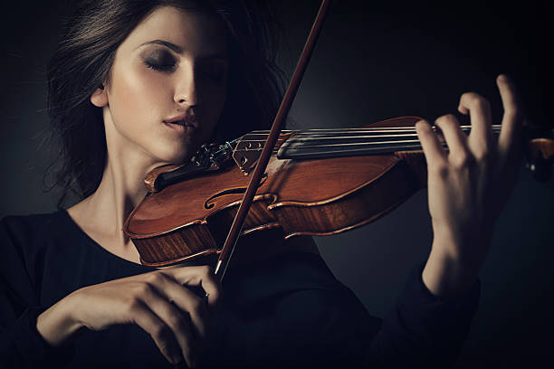 Female violinist playing a violin outdoors in a music pavilion or bandstand. About 25 years old, Caucasian woman.