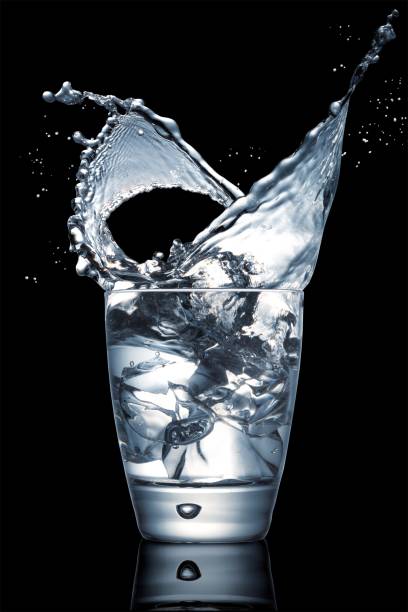 Closeup shot of an impressive water splash in a glass cup on a black background