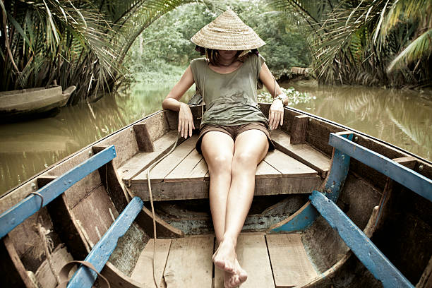 Woman sitting in wooden canoe in river of jungle stock photo