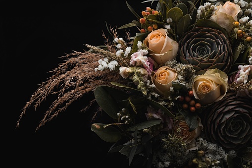 A closeup shot of a luxurious bouquet of orange and brown roses on a black background