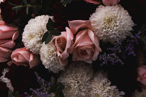 A closeup shot of a luxurious bouquet of pink roses and white flowers on a black background